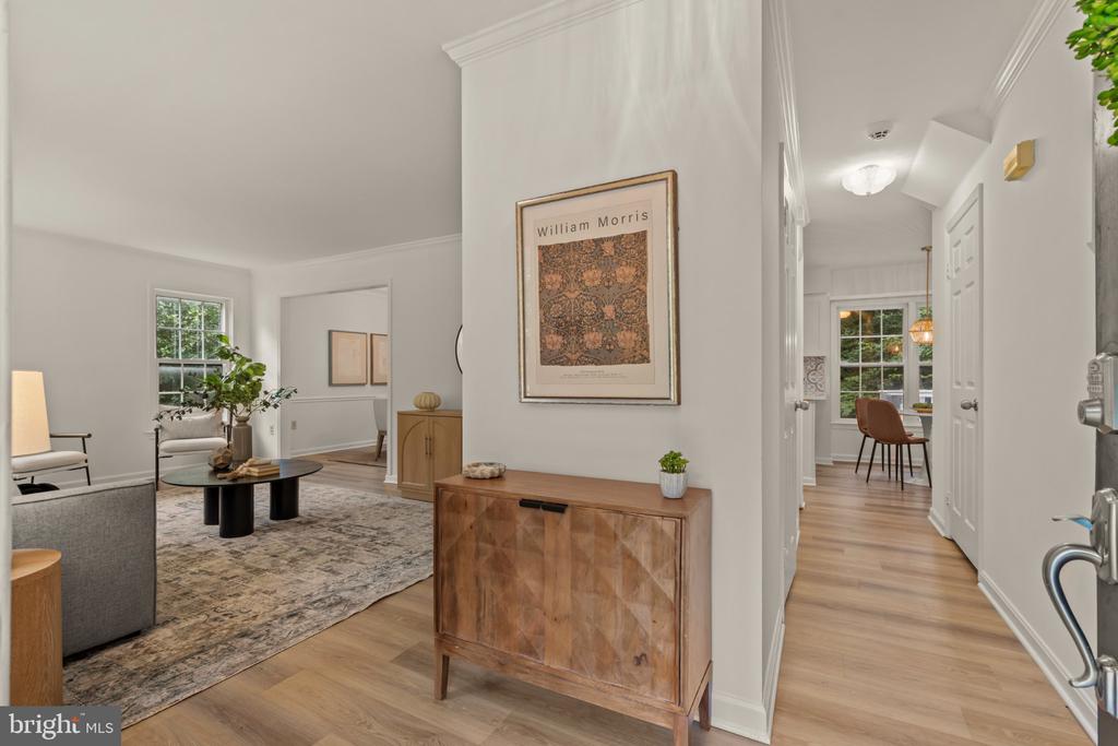 Entry hallway opening onto a furnished living room, with hardwood floors and framed William Morris artwork.