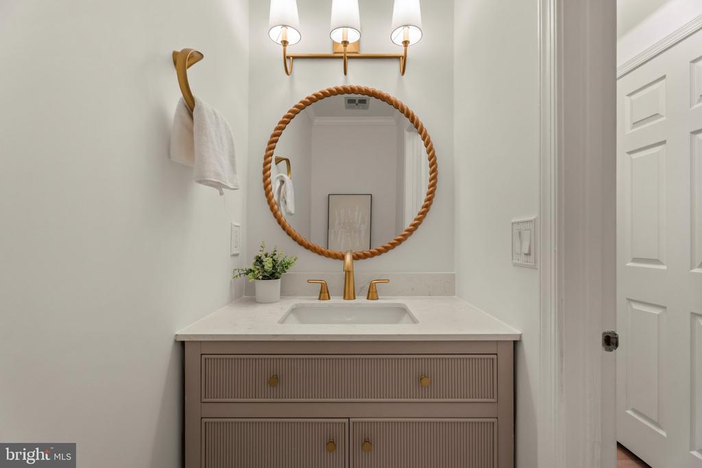 Bathroom vanity with a rope-framed round mirror and brass fixtures.