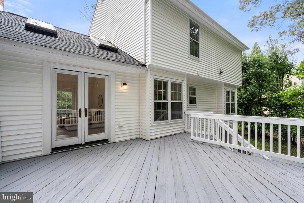 White-sided home's spacious gray deck with double glass doors and white railing.