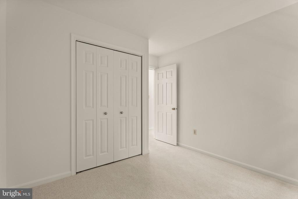 Empty carpeted room with a double-door closet and an open door to the hallway.