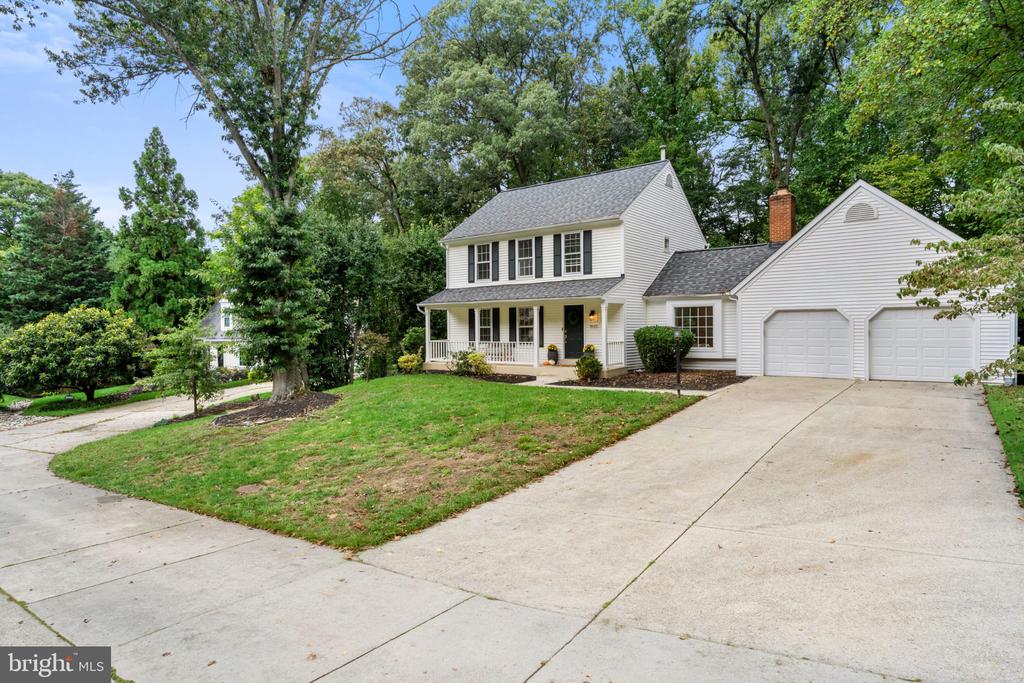 White two-story house with black shutters, a covered porch, and an attached two-car garage.