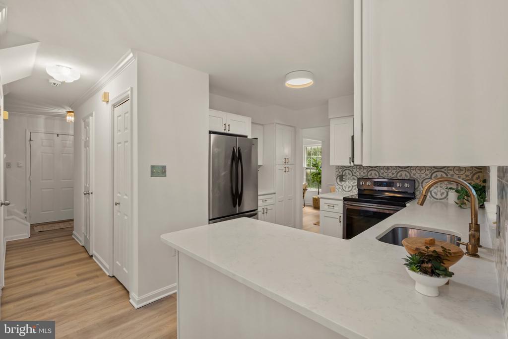 Kitchen with a large quartz island, white cabinets, stainless steel appliances, and patterned backsplash.
