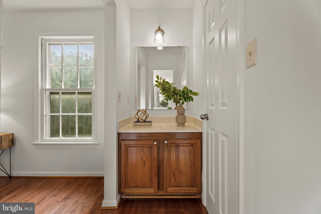 Bathroom vanity with a wood cabinet and mirror beside a large window.