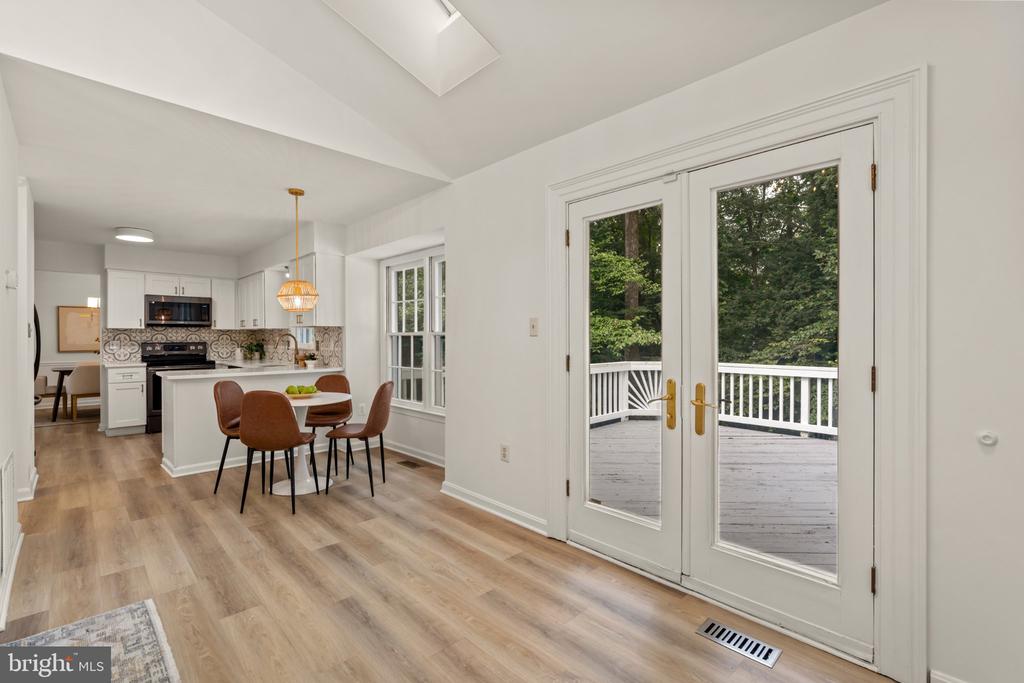 Kitchen and dining area with French doors opening onto a tree-lined deck.