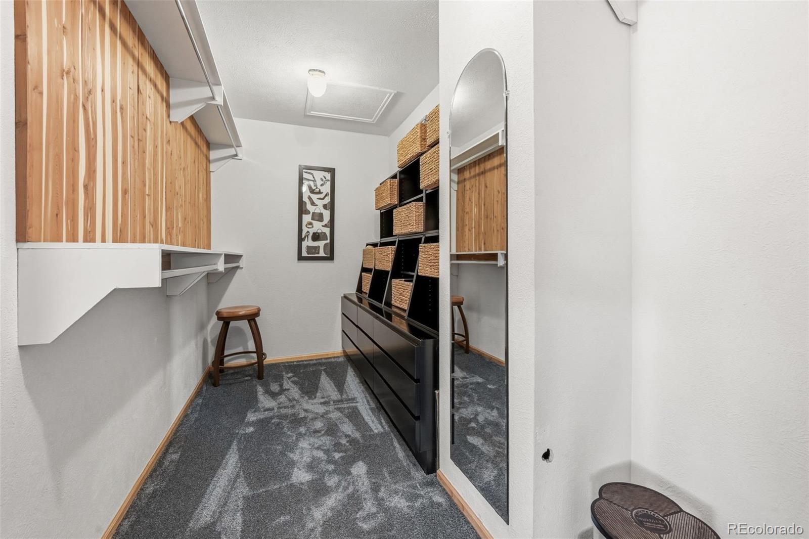 Walk-in closet with woven storage baskets, wood paneling, and a full-length mirror.