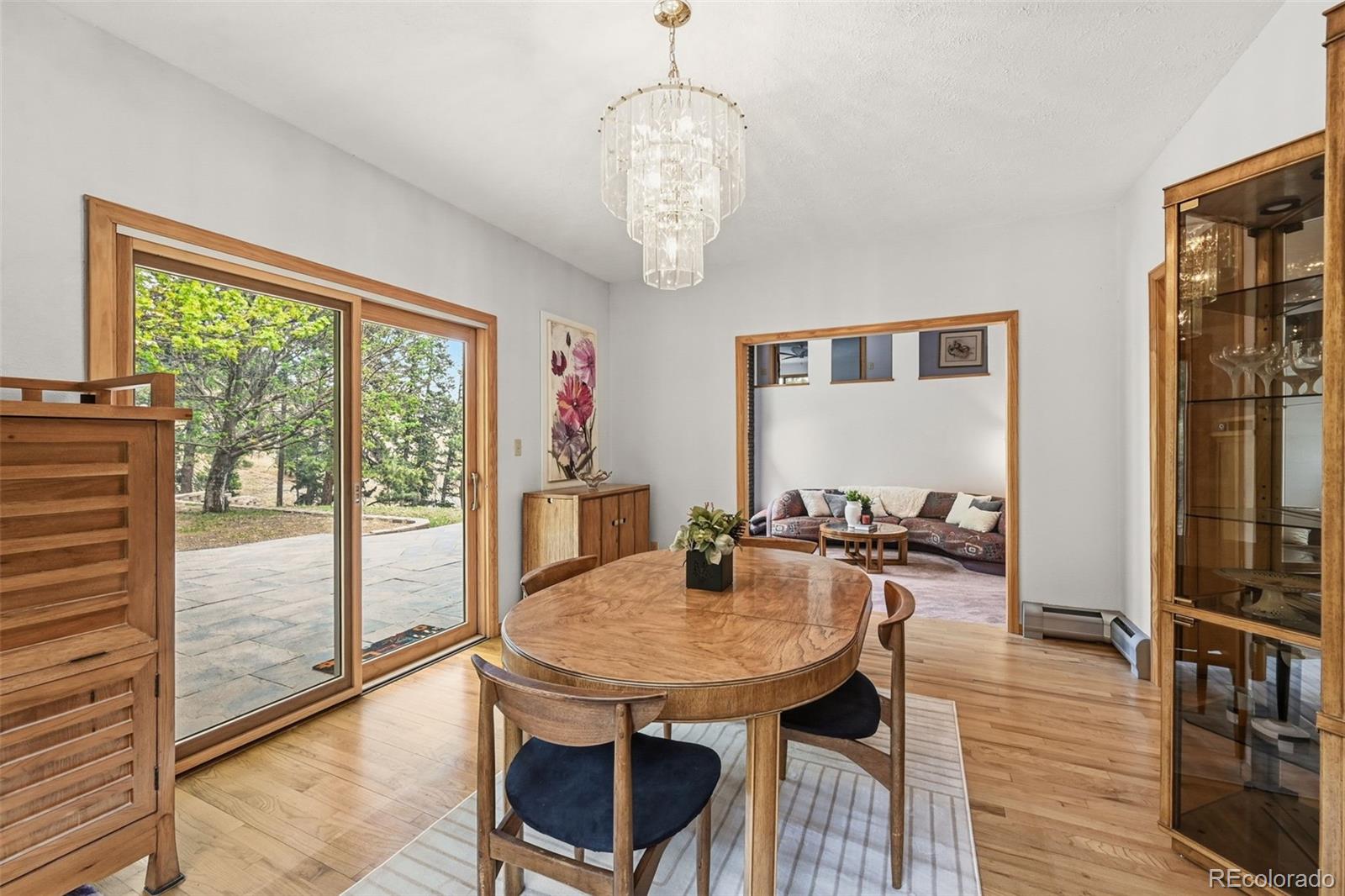Dining room with an oval wood table, crystal chandelier, and sliding doors to a patio.