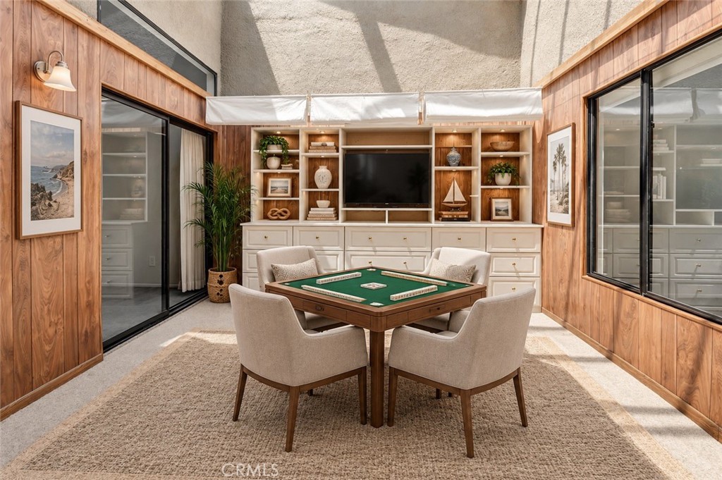 Game room with a green felt table, four chairs, wood-paneled walls, and built-in television cabinetry.