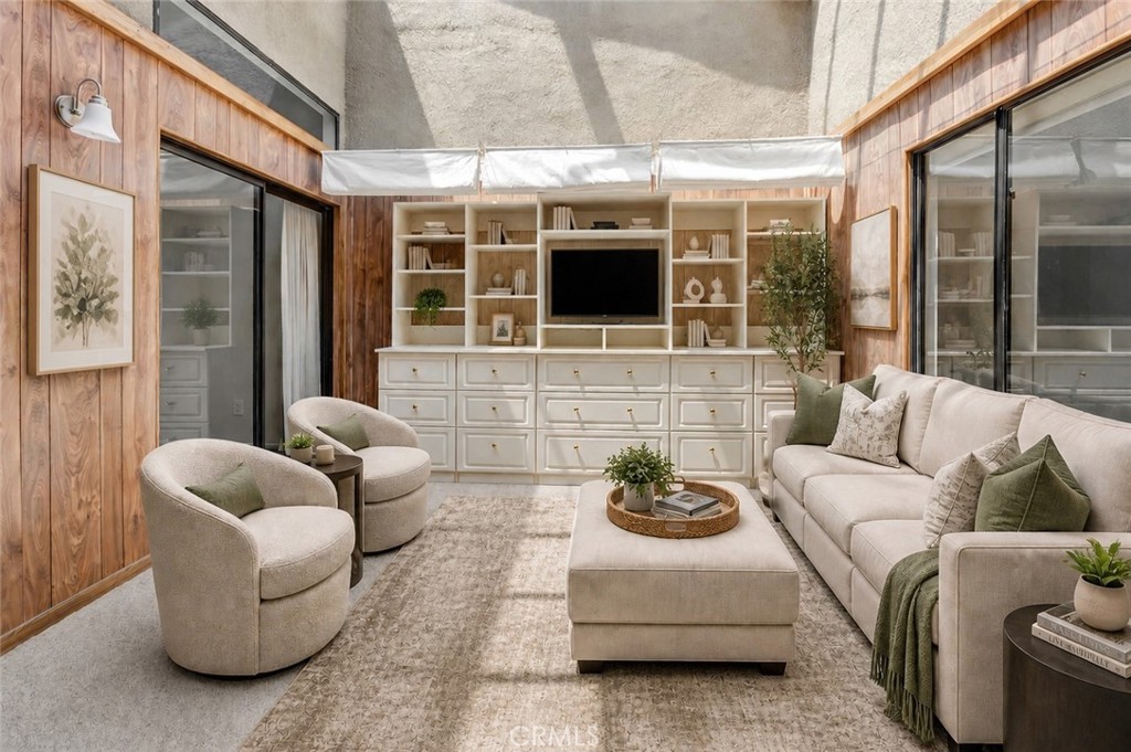 Living room with built-in shelving and television, cream seating, and warm wood-paneled walls.