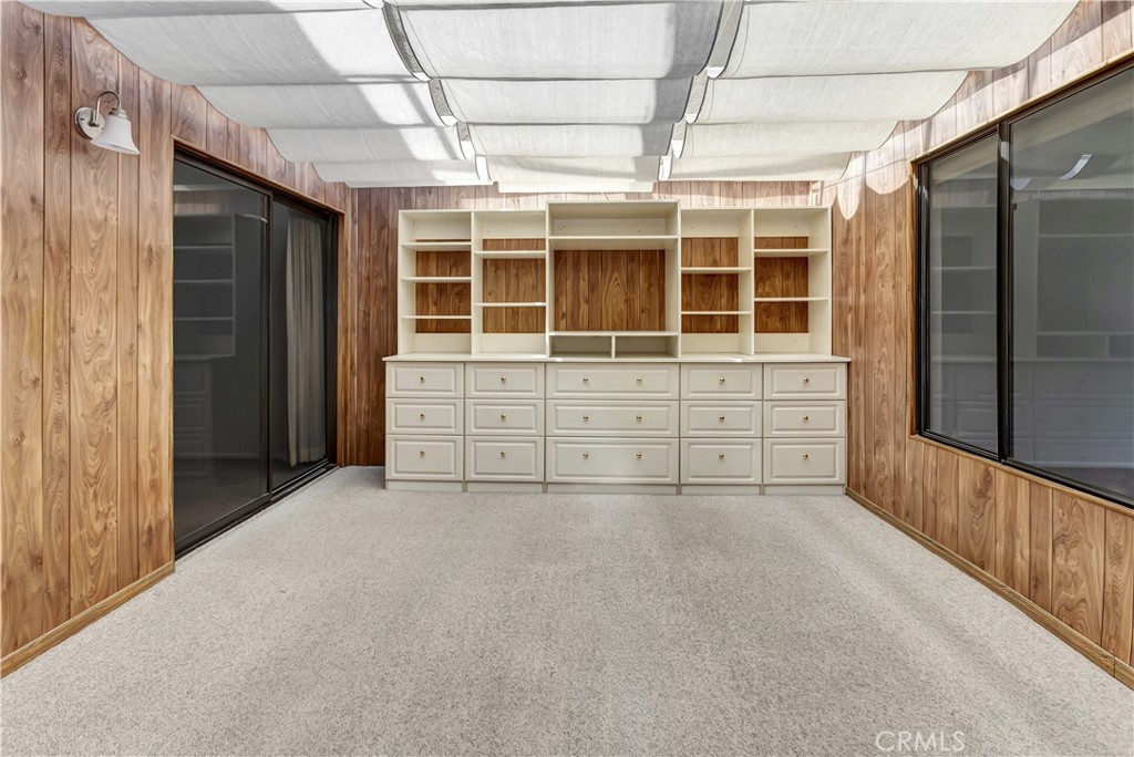 Dressing room with built-in white shelves and drawers against wood-paneled walls.