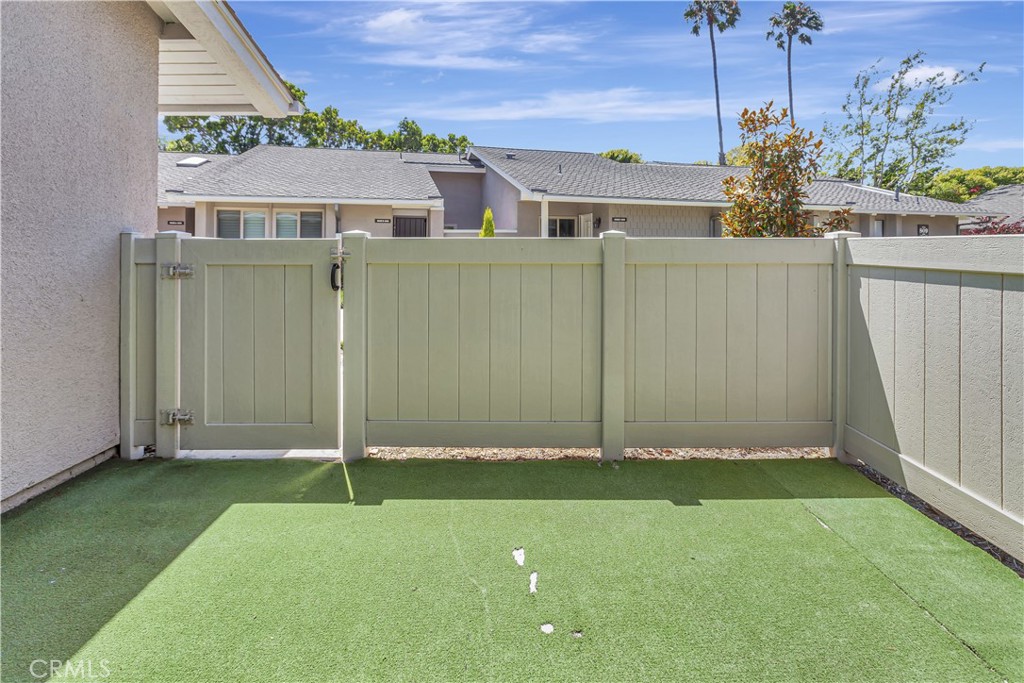 Enclosed patio with artificial turf and a pale privacy fence and gate.