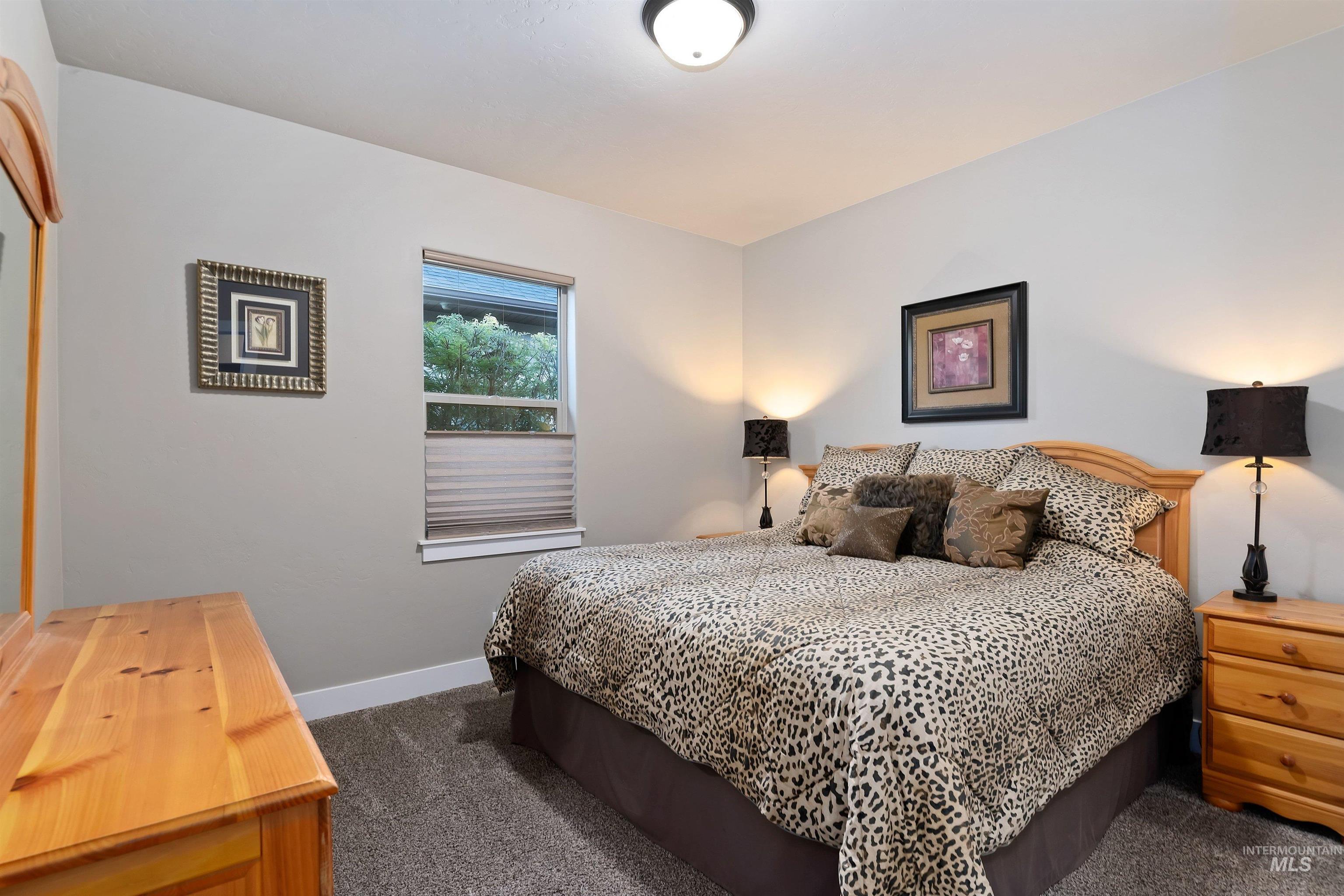 Bedroom with a king-size bed in patterned bedding and light wood furniture.