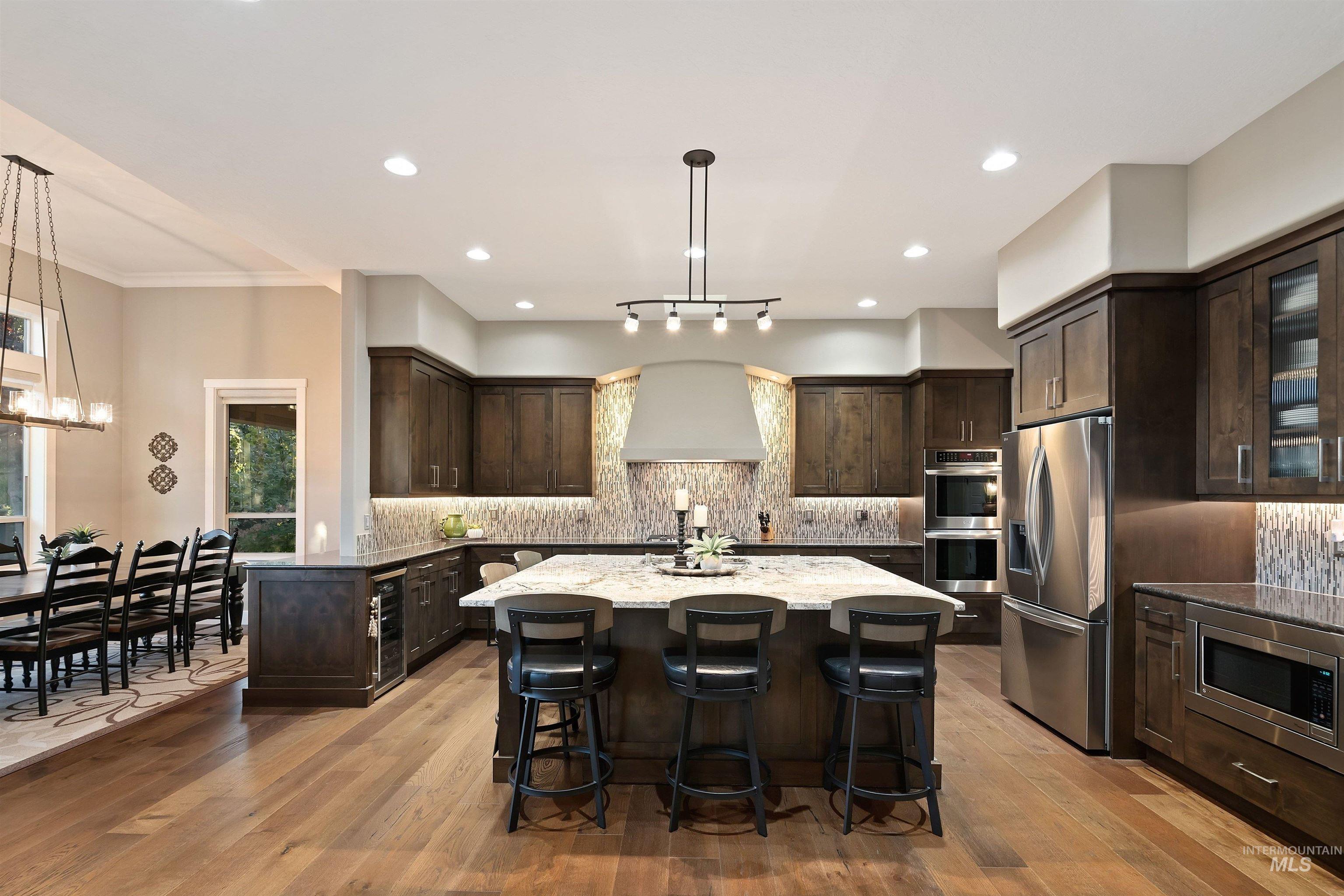 Kitchen with dark wood cabinets, stainless steel appliances, and a large island with three stools.