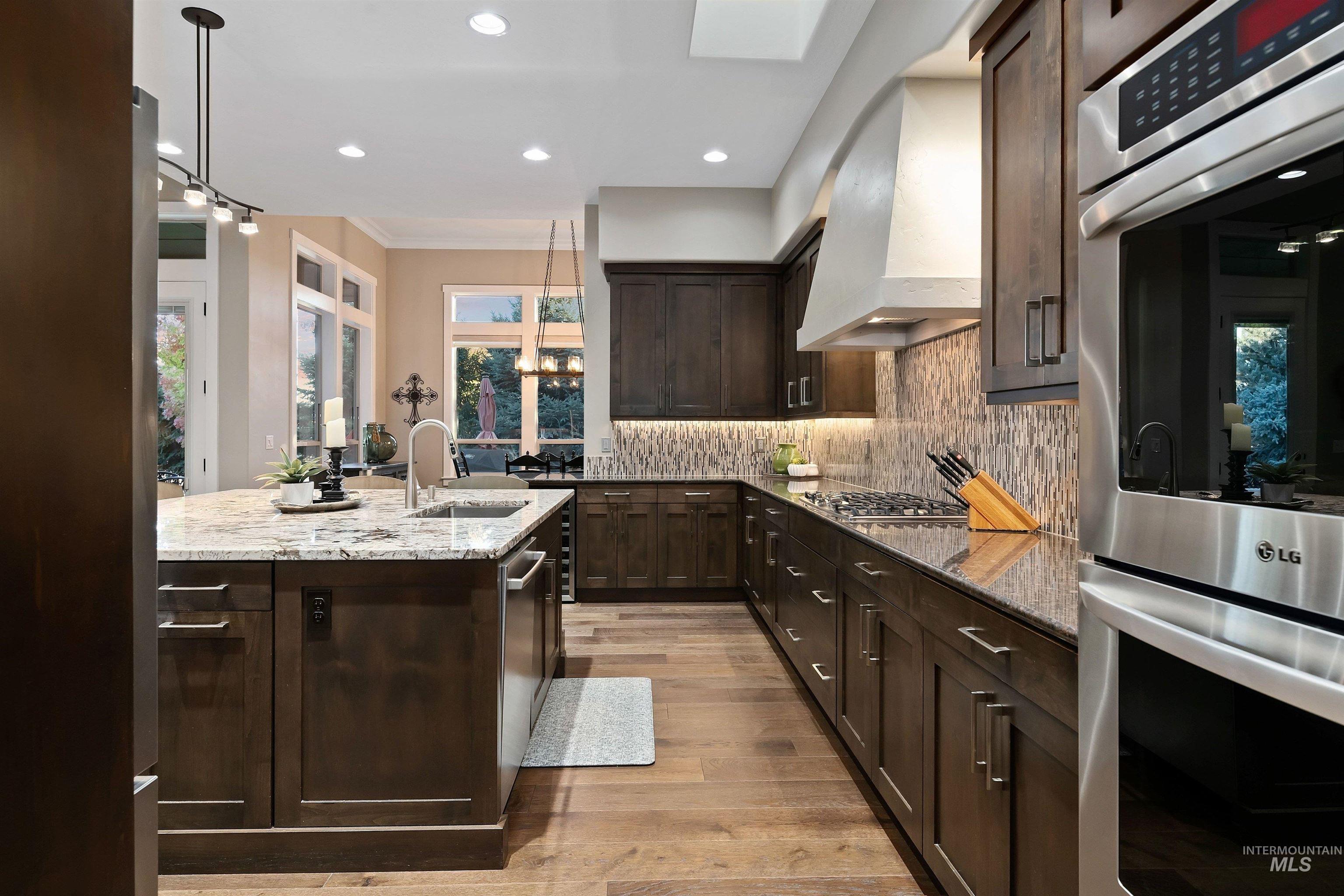 Modern kitchen with dark wood cabinets, granite island, stainless steel appliances, and mosaic tile backsplash.