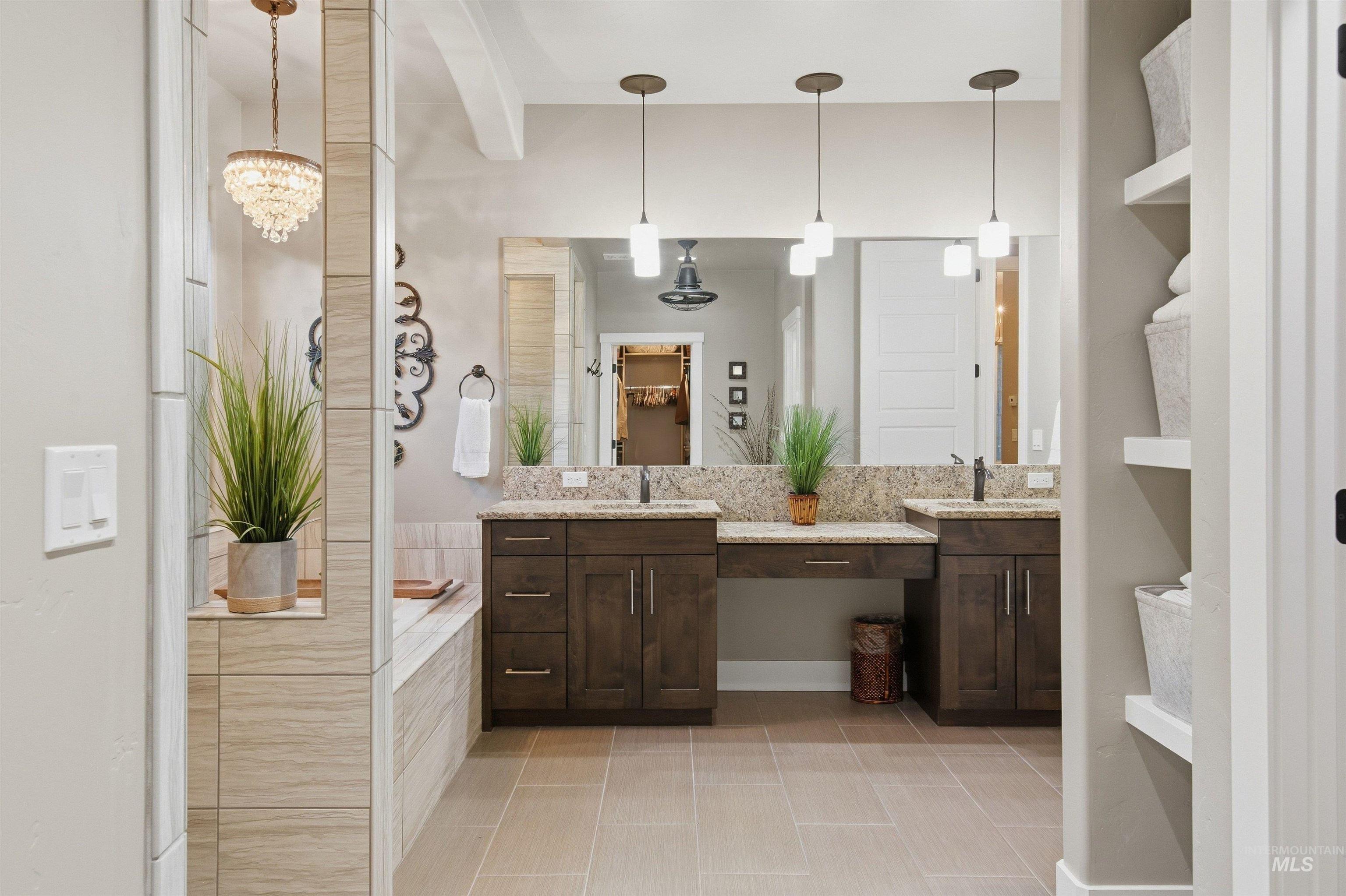 Primary bathroom with a double dark-wood vanity, granite counters, and a tiled tub area.