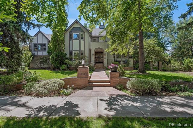 Two-story house with a brick-bordered walkway and mature trees shading the front lawn.