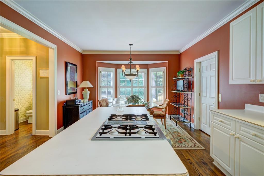 Kitchen with a large white cooktop island and a bright bay-window dining area.