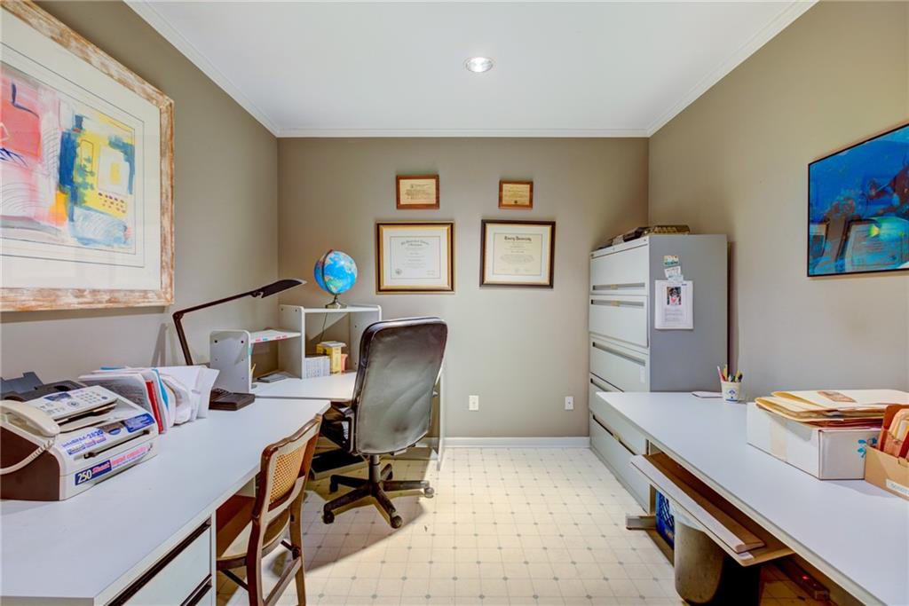 Furnished home office with white desks, a gray filing cabinet, framed artwork, and a globe.