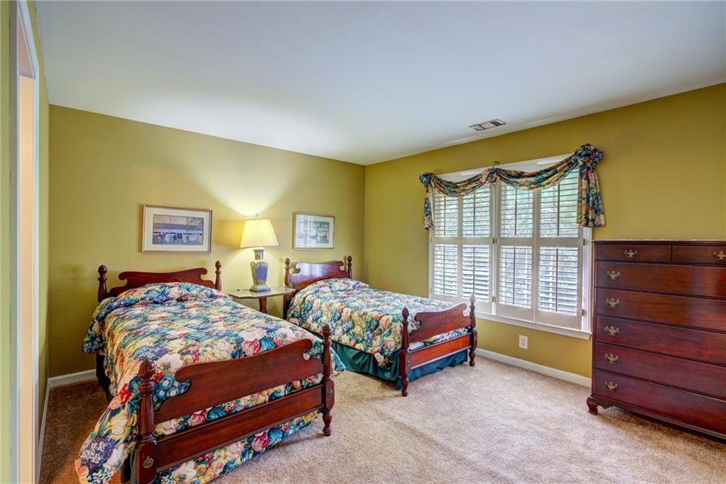 Bedroom with two wooden twin beds, floral quilts, shuttered windows, and a wooden dresser.