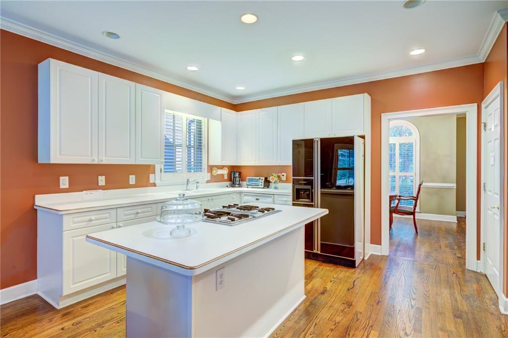 Kitchen with a large cooktop island, white cabinetry, and warm orange walls.
