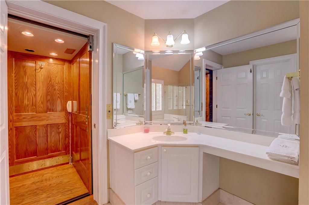 Bathroom with a long white vanity beside a wood-paneled sauna with a built-in bench.