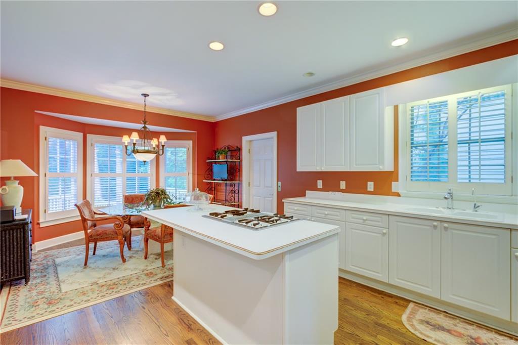 Kitchen with a large cooktop island, white cabinetry, and a dining nook against red-orange walls.