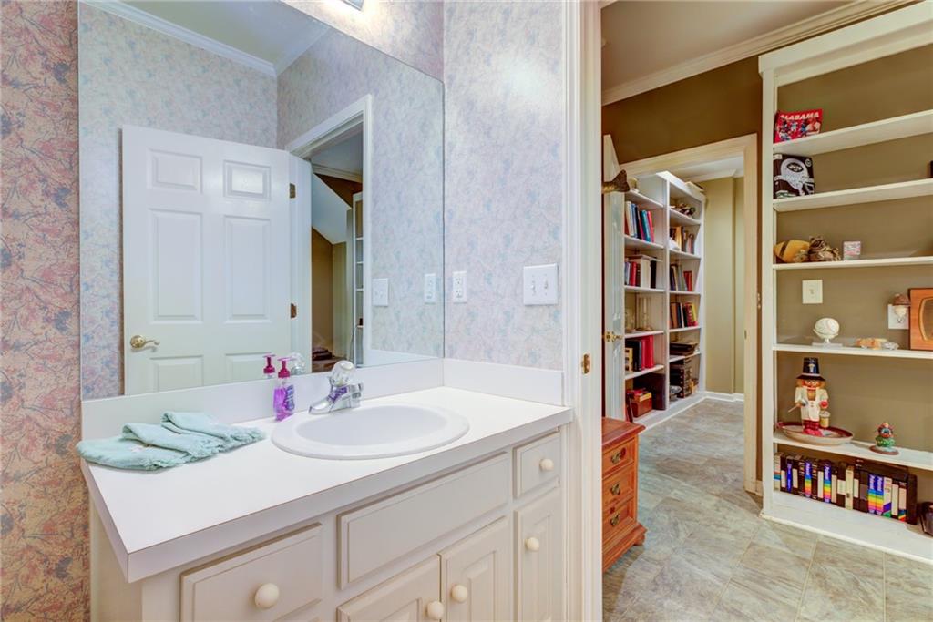 Bathroom with a white vanity and large mirror beside a tiled room with built-in shelves.