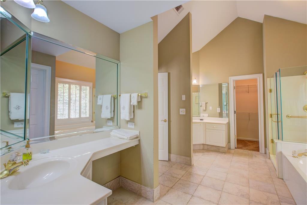 Spacious bathroom with a long white vanity, large mirrors, and tiled flooring.