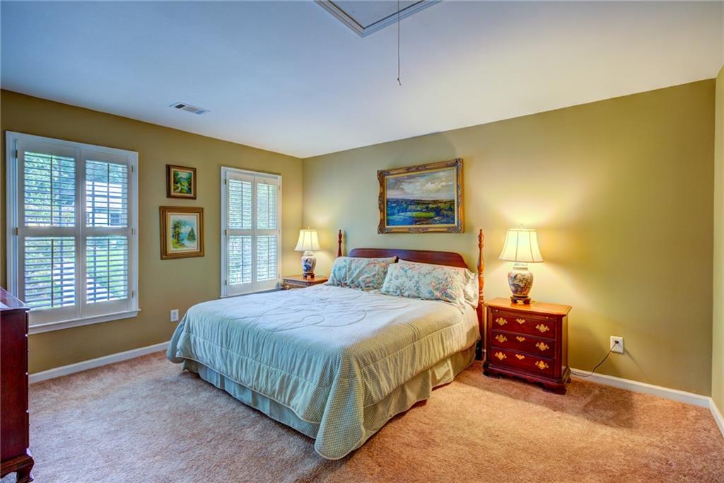 Bedroom with a large bed, shuttered windows, and matching bedside tables and lamps.