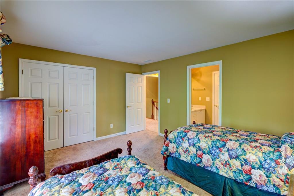 Bedroom with two floral-quilted beds, olive-green walls, and a doorway to the bathroom.