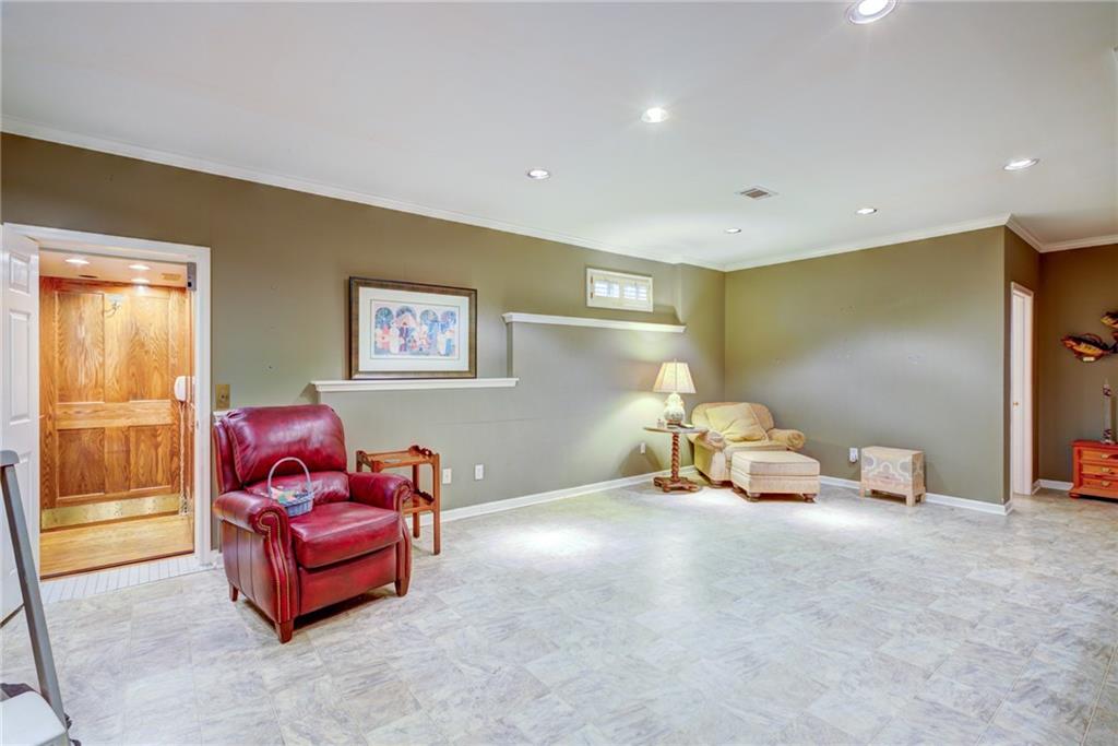 Spacious tiled room with a red leather recliner, cream chaise lounge, and wood-paneled sauna doorway.