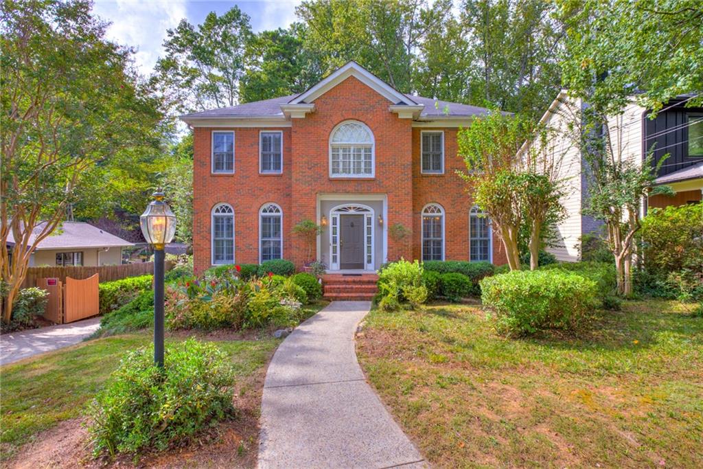 Two-story red-brick home with arched windows and a curved front walkway.