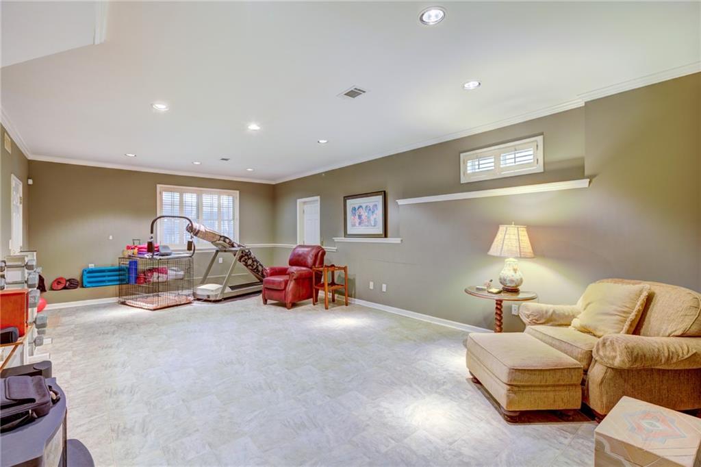 Recreation room with a treadmill, red leather chair, and beige sectional sofa.
