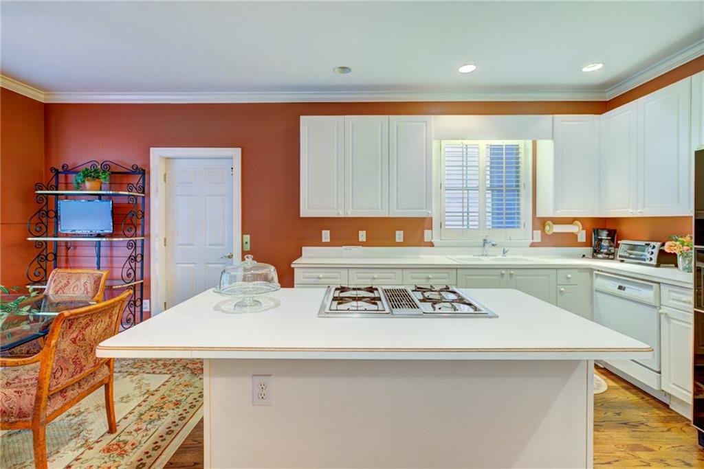Kitchen with a large white island and cooktop, white cabinetry, terracotta walls, and hardwood floors.
