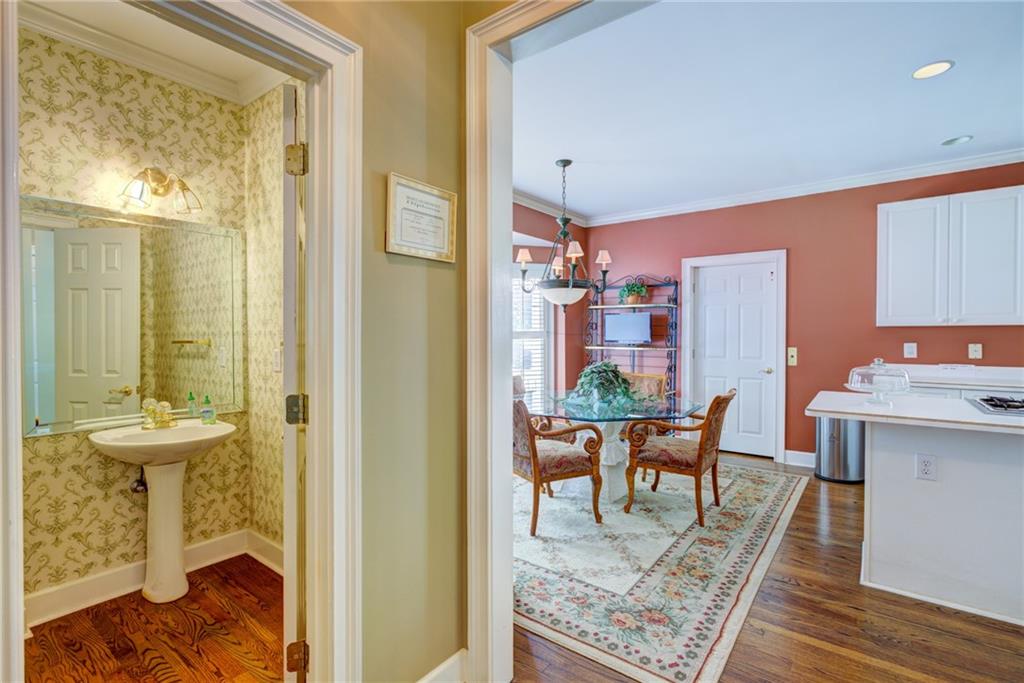 Patterned powder room with a pedestal sink opens onto a furnished dining area and kitchen.