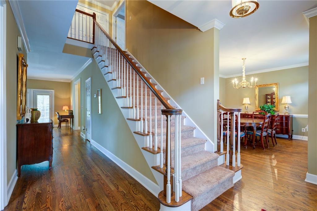 Entry hall with carpeted staircase and hardwood floors opening to a formal dining room.