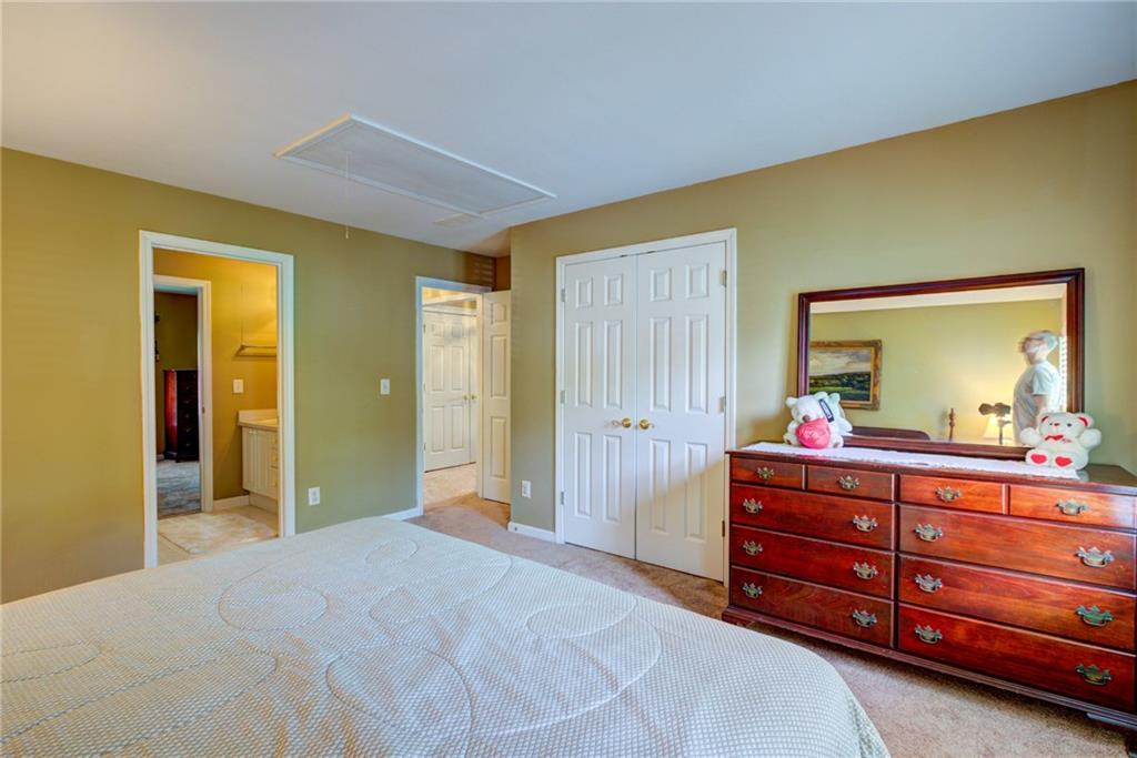 Bedroom with a patterned bed, wooden dresser and mirror, and an open doorway to a bathroom.