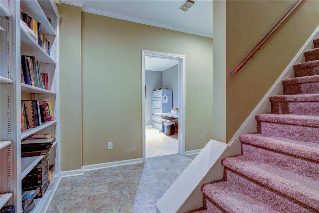 Hallway with built-in bookshelves and carpeted stairs beside a doorway to a utility room.