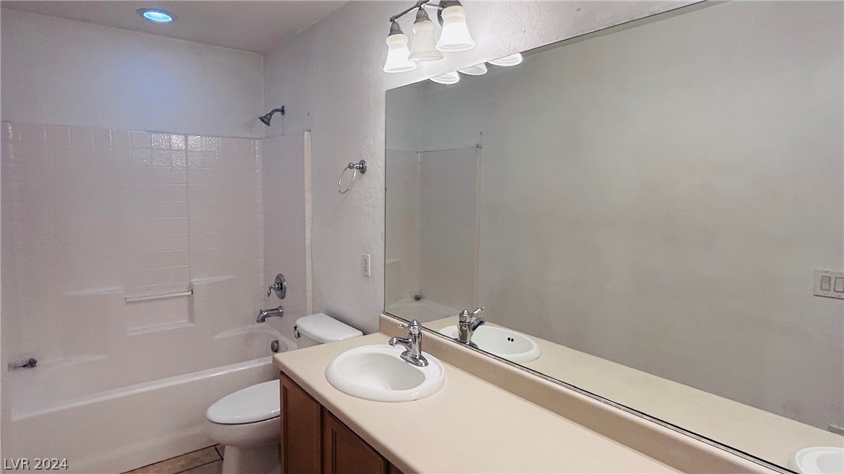 Bathroom with a white tub, tiled surround, and single-sink vanity beneath a large mirror.