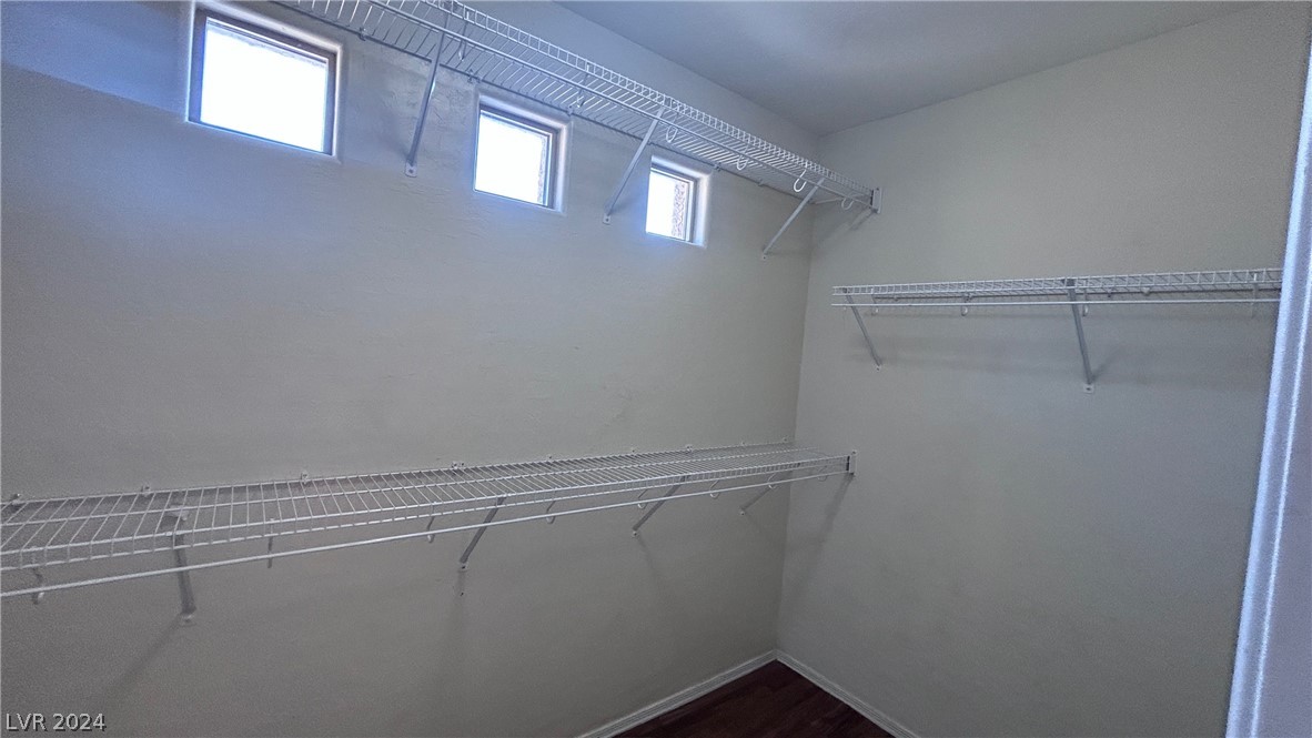 Walk-in closet with wire shelving on three walls, high windows, and dark wood flooring.