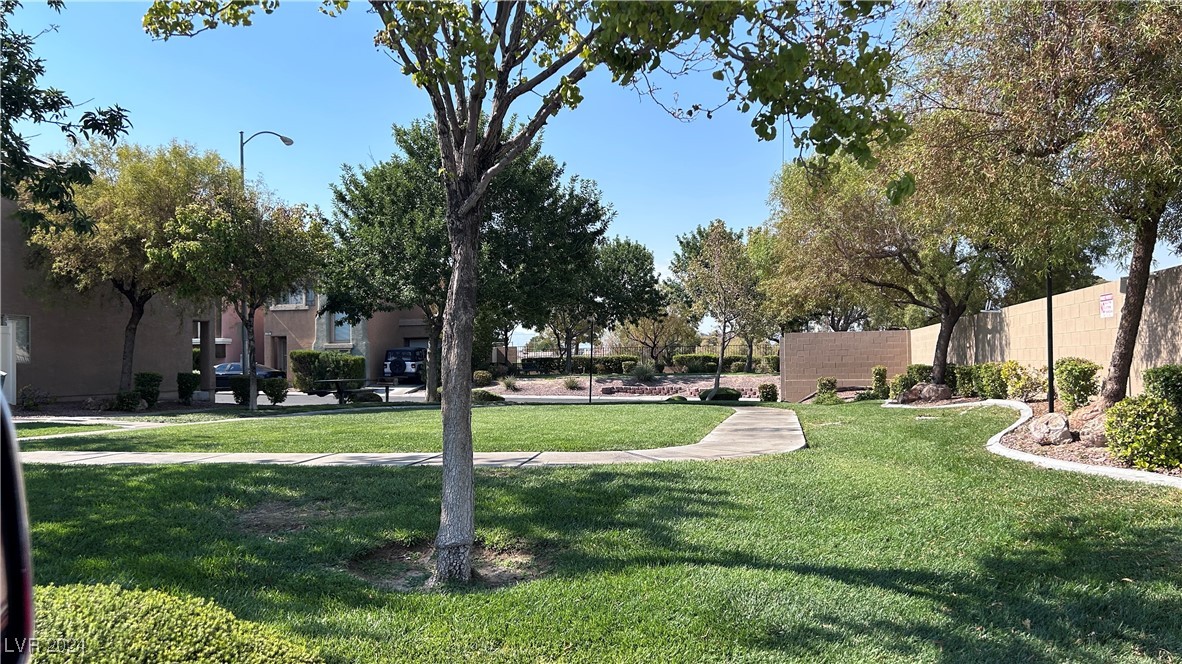 Community courtyard with a green lawn, curving walkways, mature trees, and residential buildings.