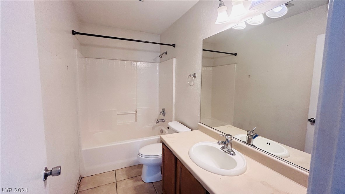 Bathroom with tub-shower, toilet, and dark wood vanity beneath a large mirror.