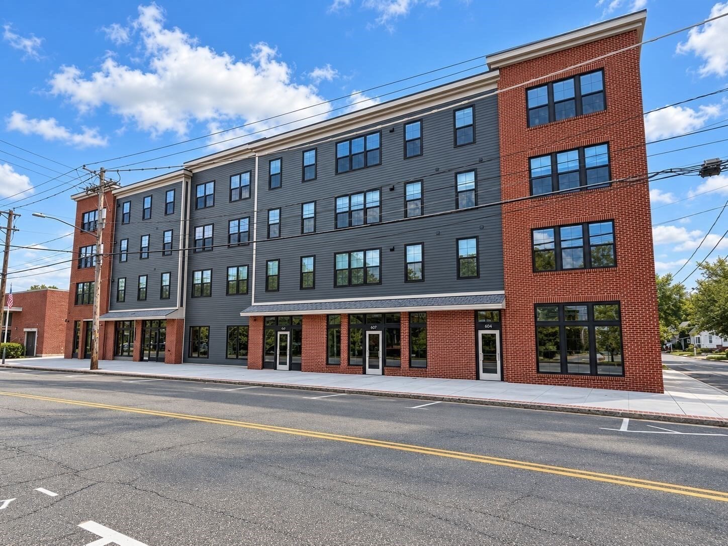 Multistory brick and gray-sided building with rows of windows and several street-level entrances.
