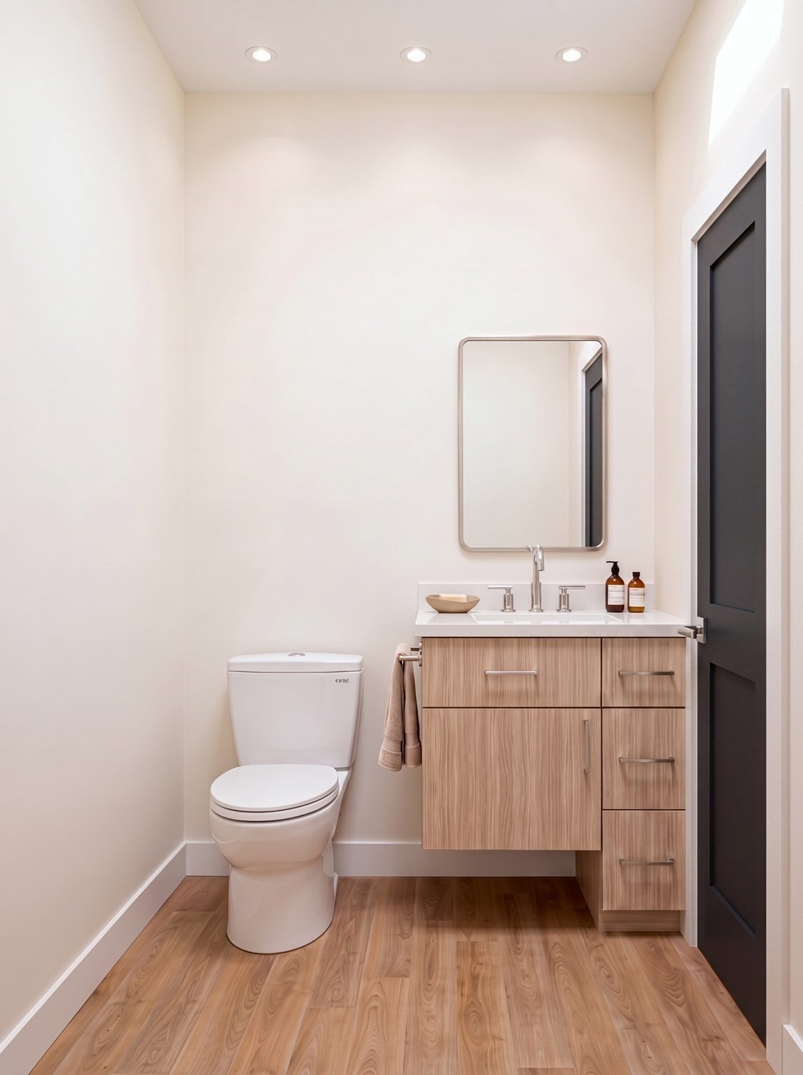 Modern bathroom with a light wood vanity, rectangular mirror, white toilet, and wood-look flooring.