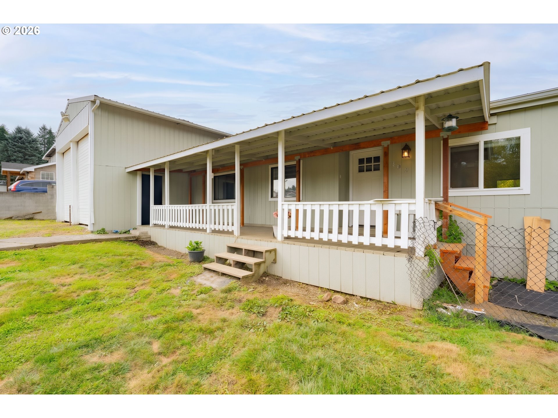 Home exterior with a long covered porch, white railings, and a grassy yard.
