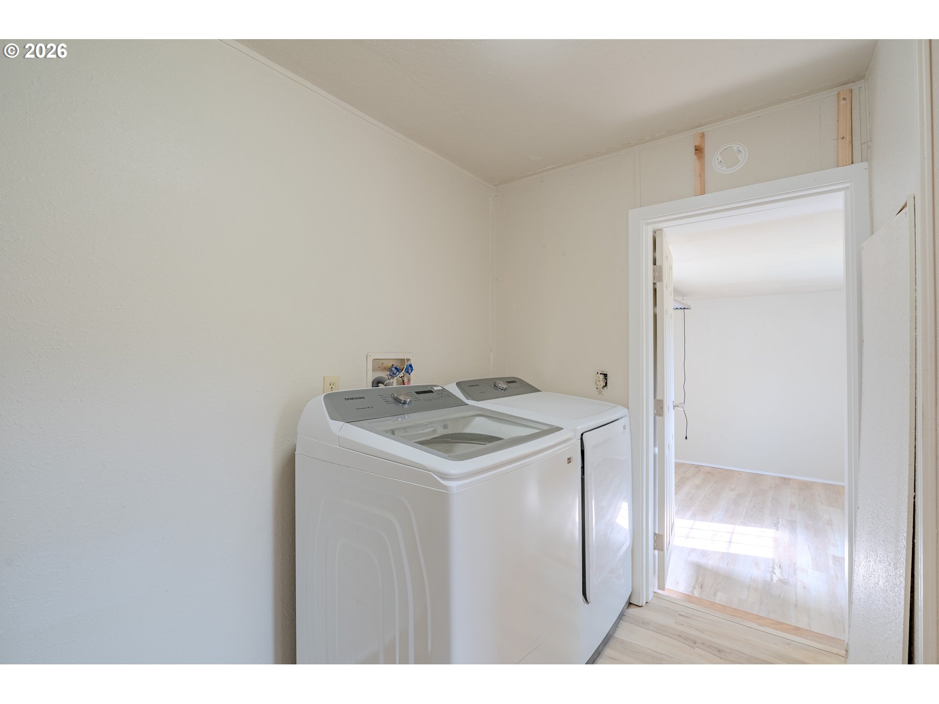 Laundry area with a top-load washer and dryer beside an open doorway.