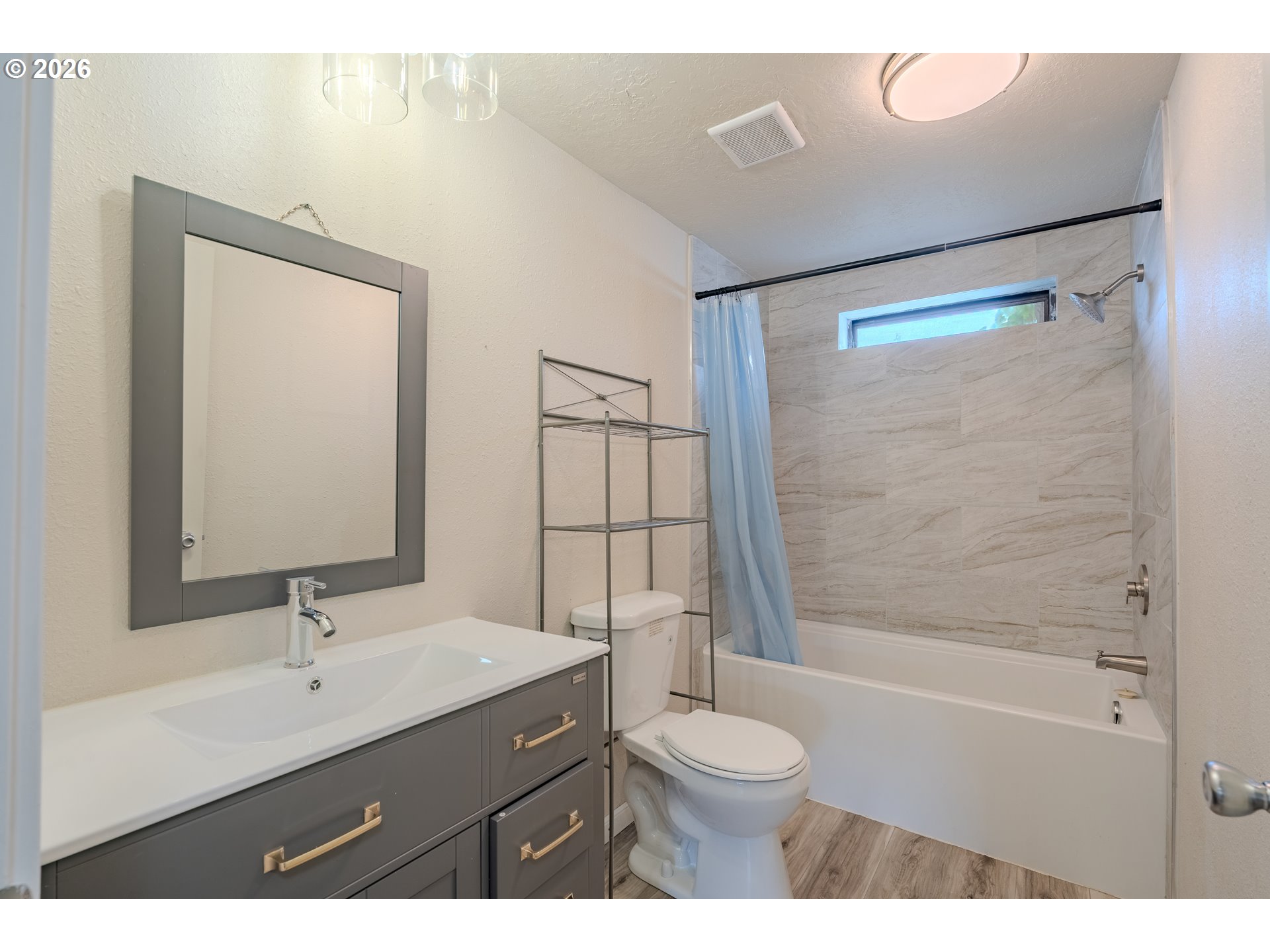 Bathroom with gray vanity, white sink, and bathtub beneath a narrow horizontal window.