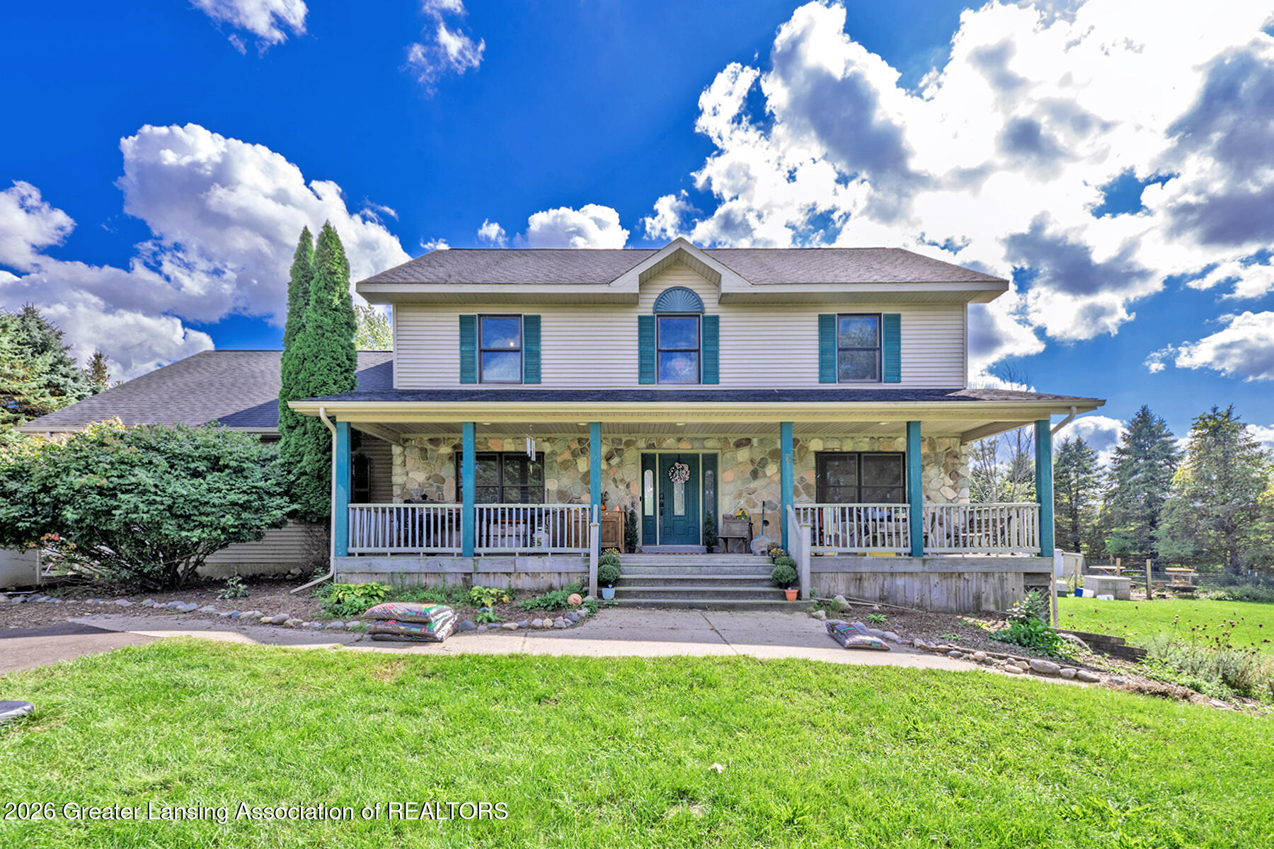 Two-story house with a stone-faced lower level and a wide covered porch.
