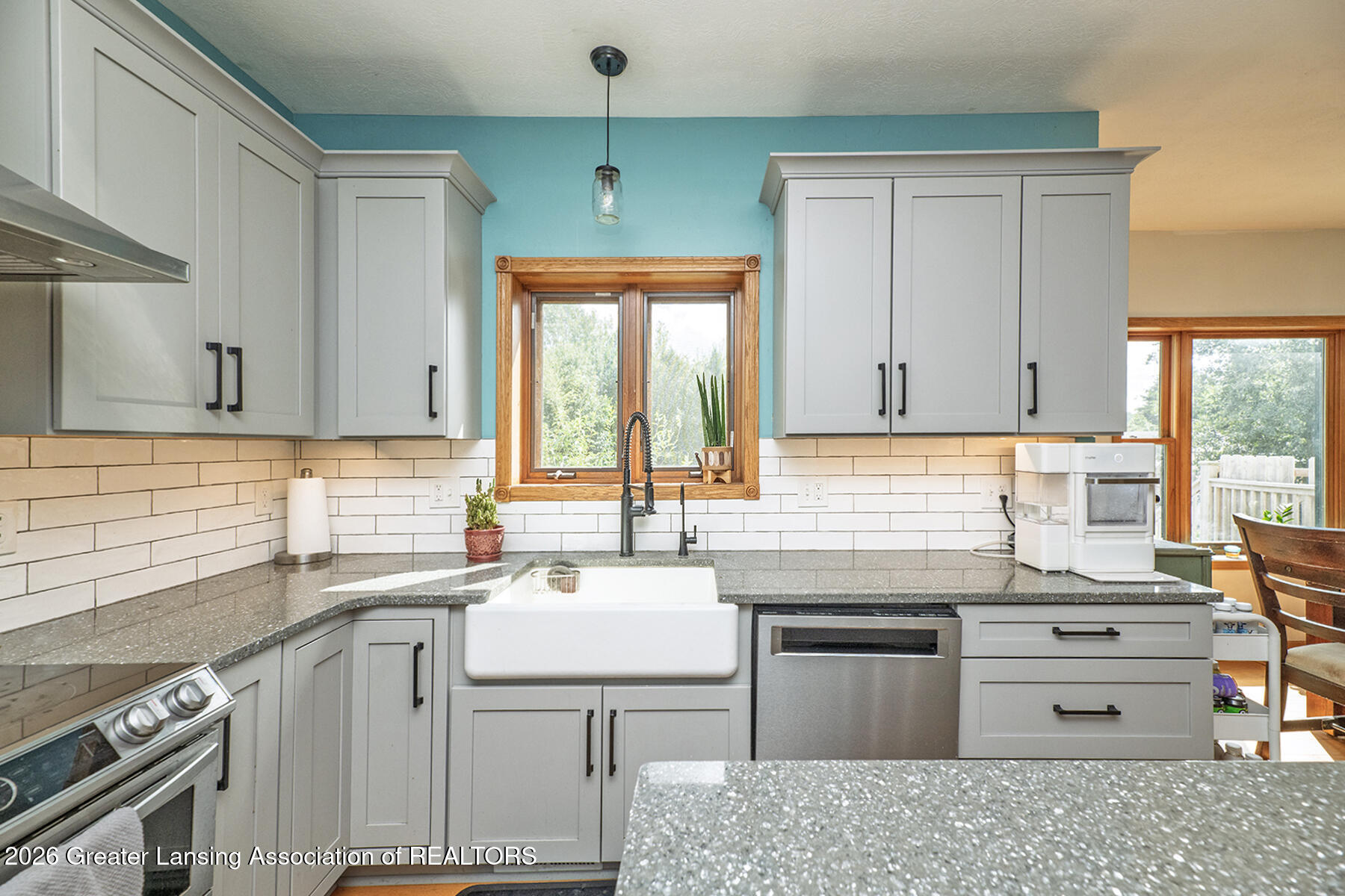 Kitchen with gray cabinets, a farmhouse sink, and a turquoise accent wall.