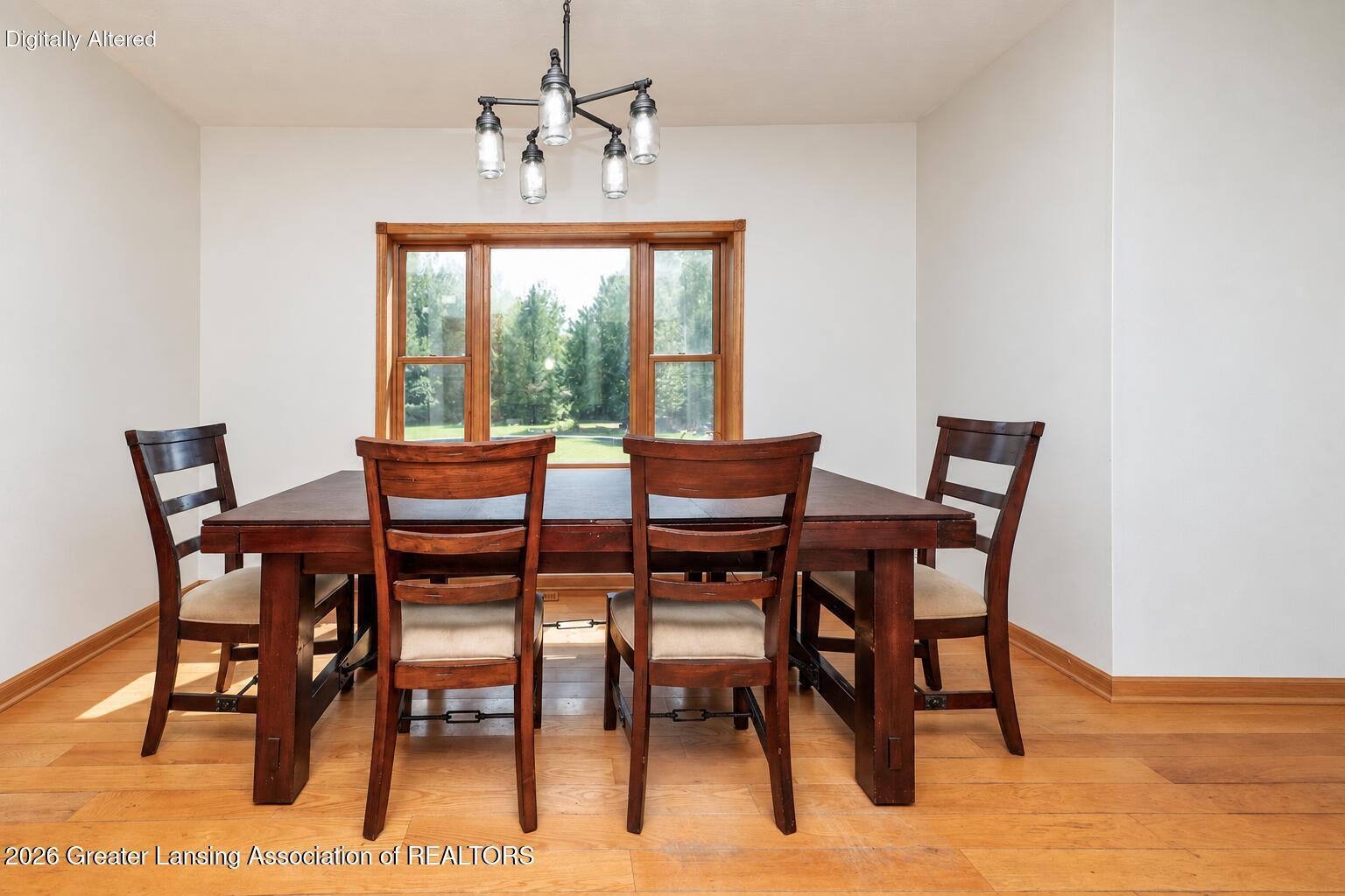 Dining room with a dark wood table and chairs, hardwood floors, and a large window.
