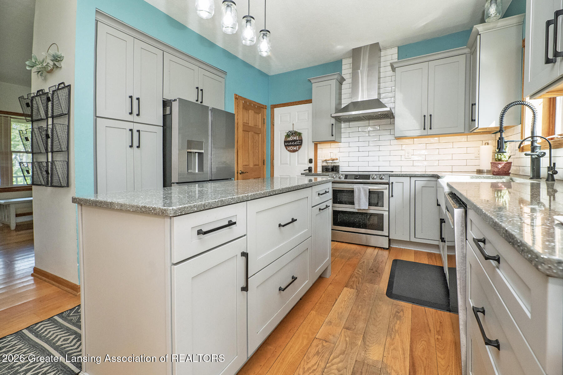 Bright kitchen with white cabinetry, granite counters, stainless appliances, and a large island.